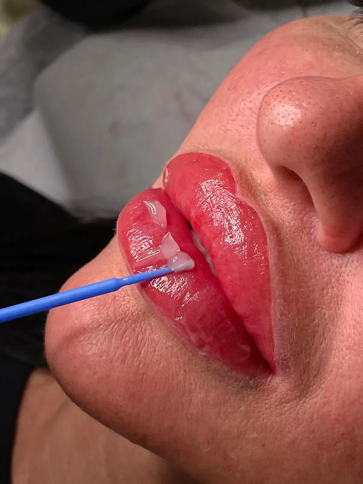Un primer plano de los labios de una mujer con un pincel azul.
