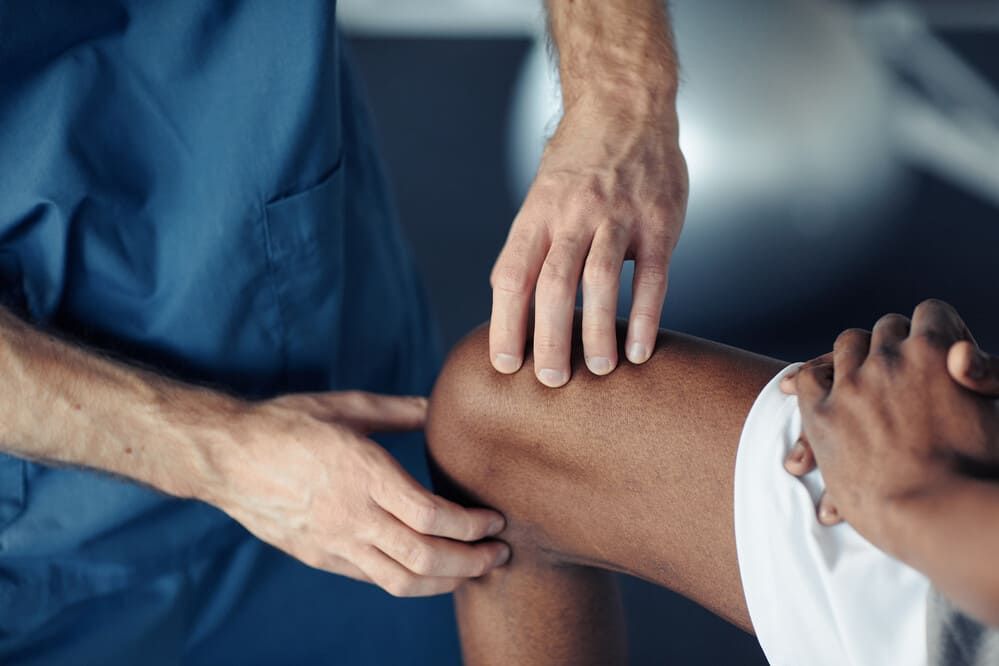 Un médico está examinando la rodilla de un paciente en un hospital.