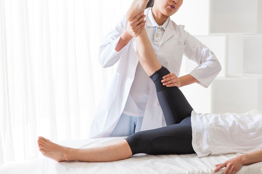 Un médico está examinando la pierna de un paciente en una cama.