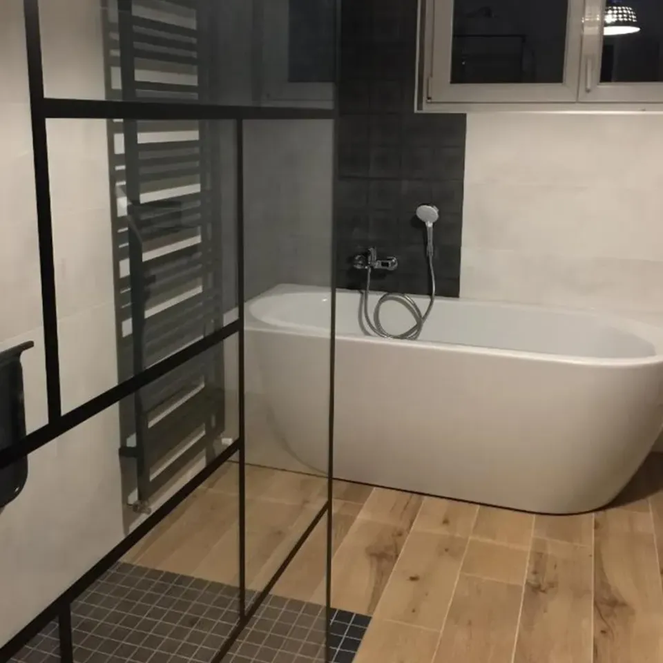 Salle de bains moderne avec baignoire îlot, douche à cadre noir et sol en bois