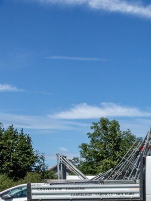 Nacelle élévatrice à flèche repliée sur un wagon métallique, sur fond de ciel bleu et d’arbres