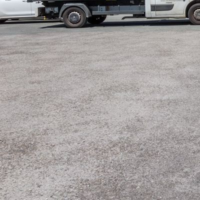 Parking en asphalte gris avec un camion partiellement visible en haut de l’image