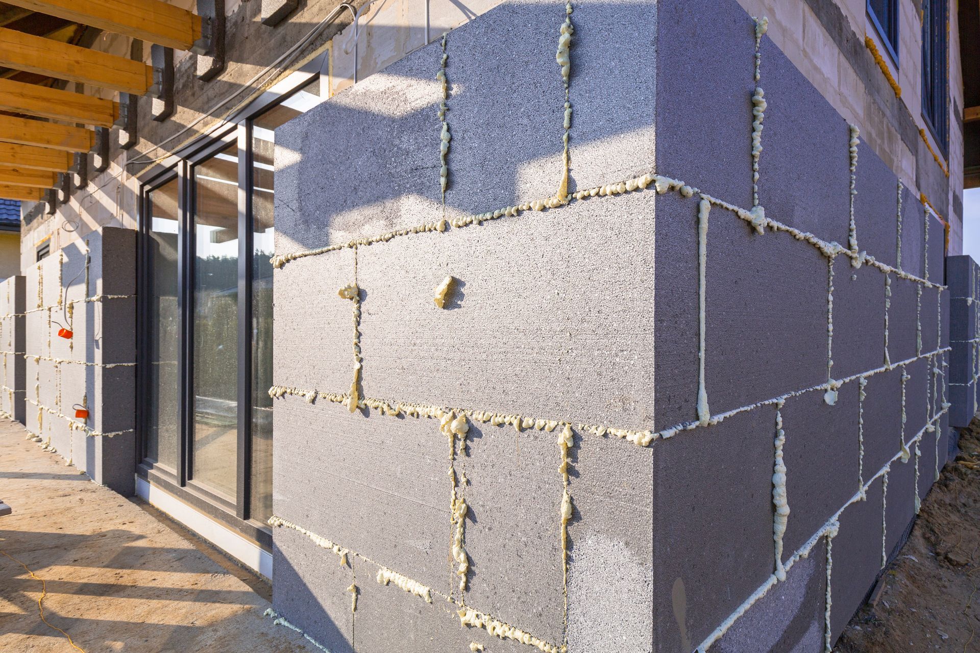 Extérieur d’un bâtiment en blocs de béton partiellement isolé, avec des portes vitrées et un angle en maçonnerie apparente
