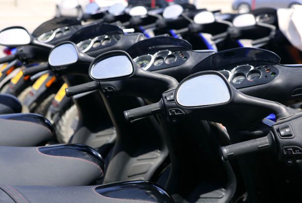 Una fila di scooter sono parcheggiati uno accanto all'altro in un parcheggio.