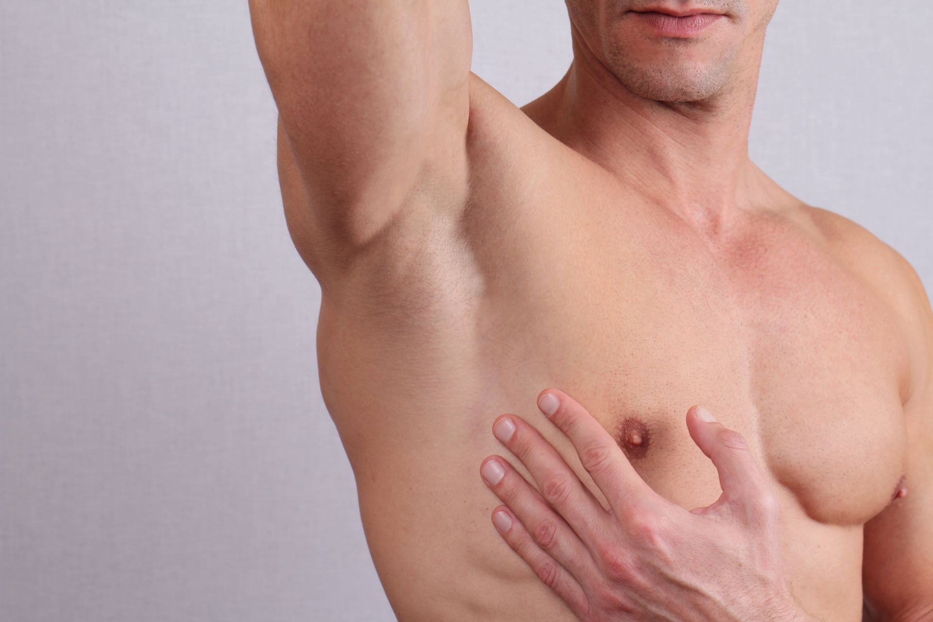 Gros plan sur le torse musclé d'un homme, épilation de la poitrine et des aisselles.