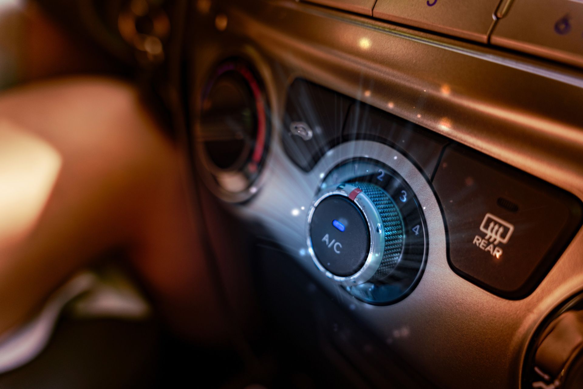 Perilla de control del aire acondicionado del automóvil con luz azul activada; el brazo derecho alcanza la misma; detalles del tablero.