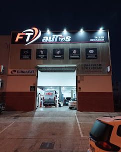 Vista nocturna de un taller mecánico con cartel iluminado: 