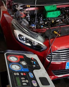 El capó del coche está abierto, la carrocería es roja. El equipo de diagnóstico está delante. Reparando el sistema de aire acondicionado.