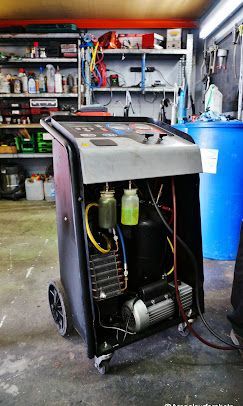 Una máquina de recuperación de aire acondicionado para automóvil de color negro y plateado en un garaje.