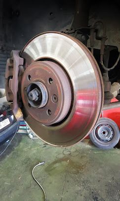 Conjunto de rotor y pinza de freno del automóvil; se observan óxido y desgaste.