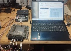 Computadora portátil conectada a la ECU (unidad de control del motor) y al dispositivo de programación con cables en un escritorio.