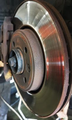 Rotor de freno de un vehículo, con desgaste y óxido. La pinza es visible a la izquierda.