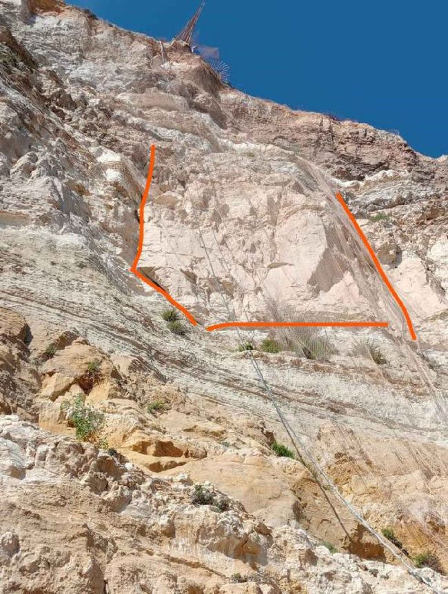 Un primer plano de un acantilado rocoso con un cielo azul de fondo.