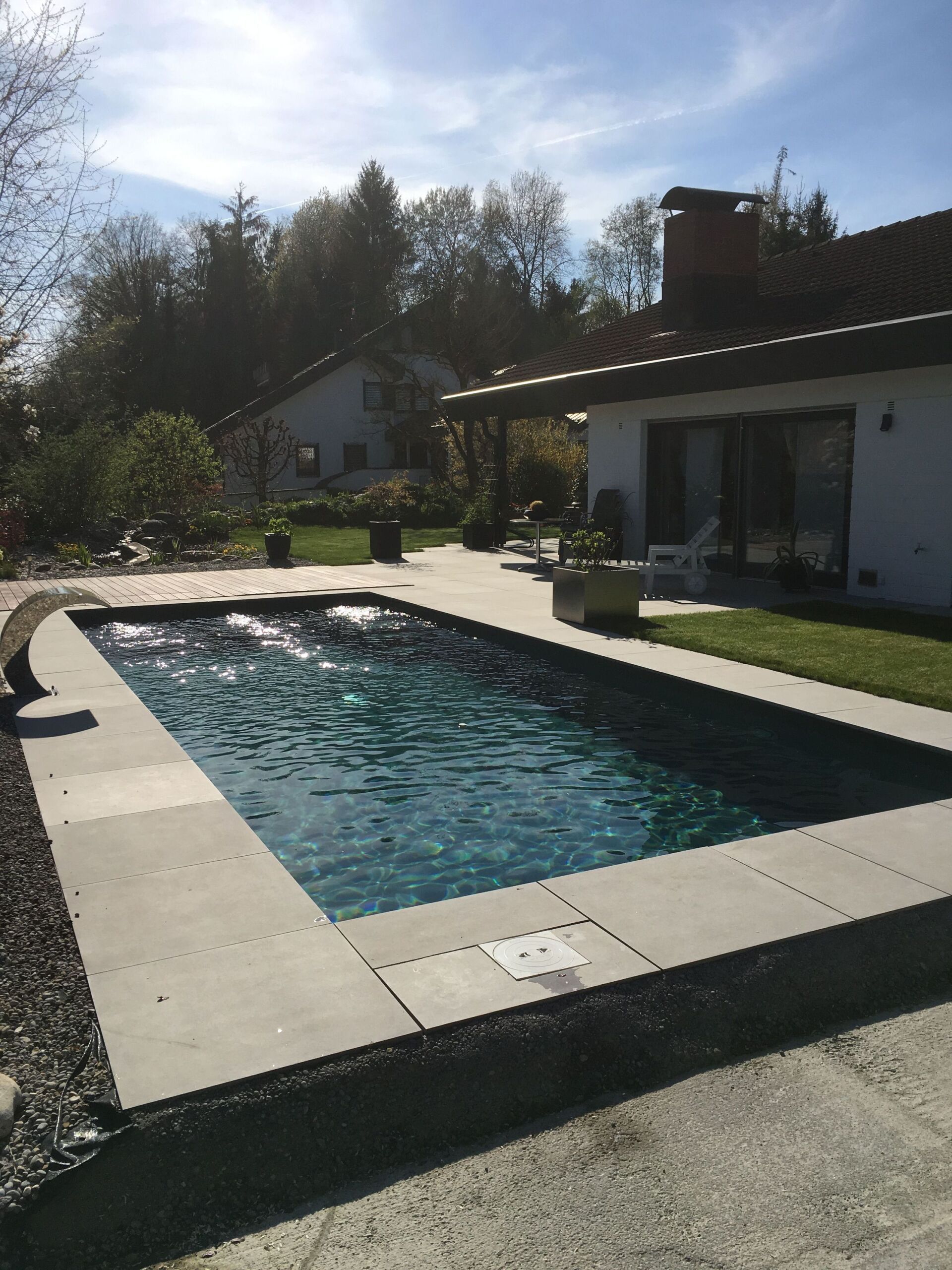 Pool mit grauem Fliesenwerk vor dem Haus