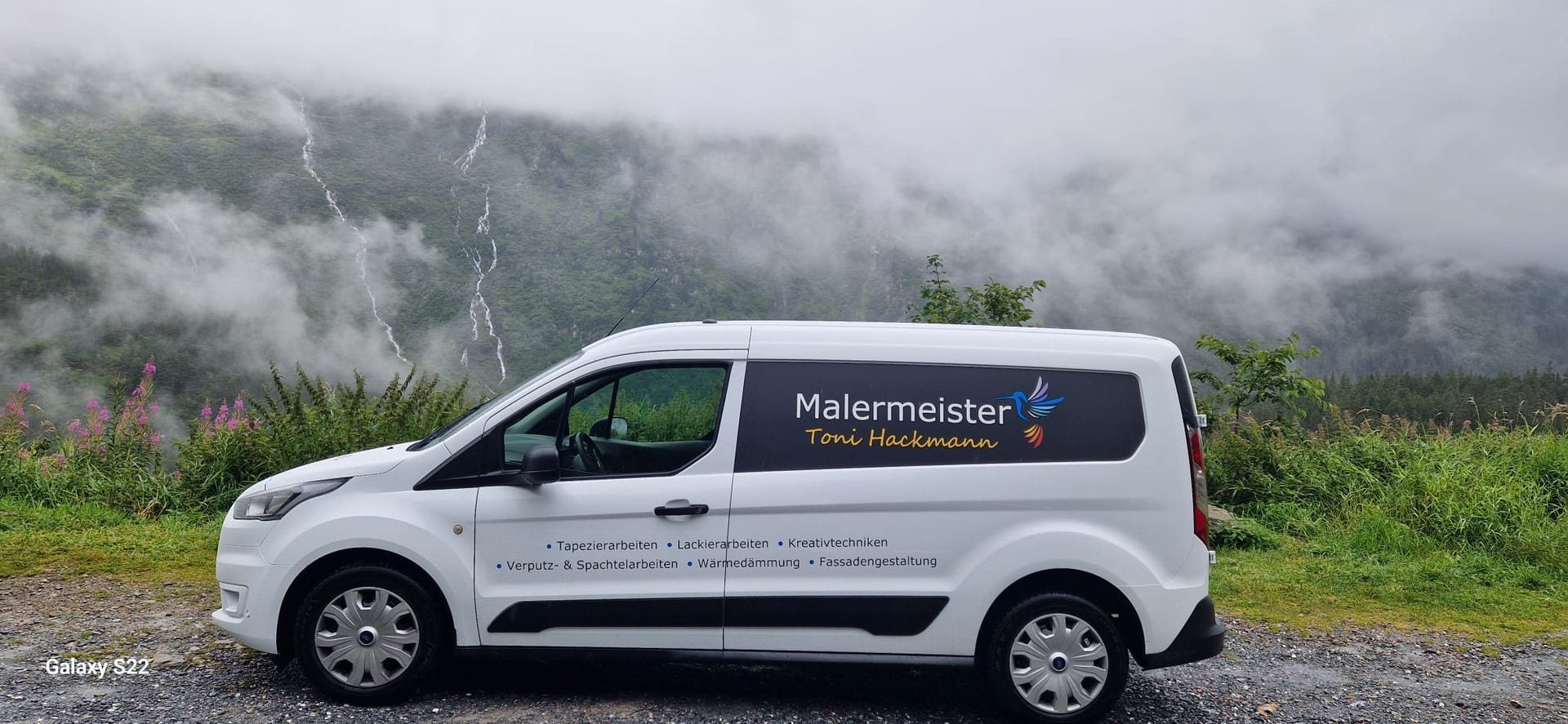 Weißer Lieferwagen mit „Müller…“-Aufschrift parkt auf einer nebligen Bergstraße
