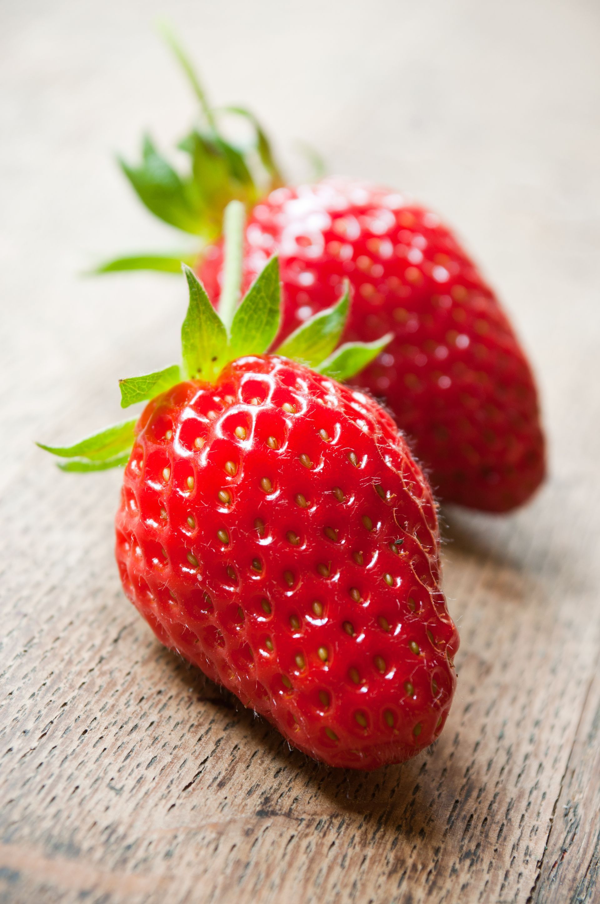 Des fraises dans une caisse en bois devant un champ de fraises, ciel bleu en arrière-plan.