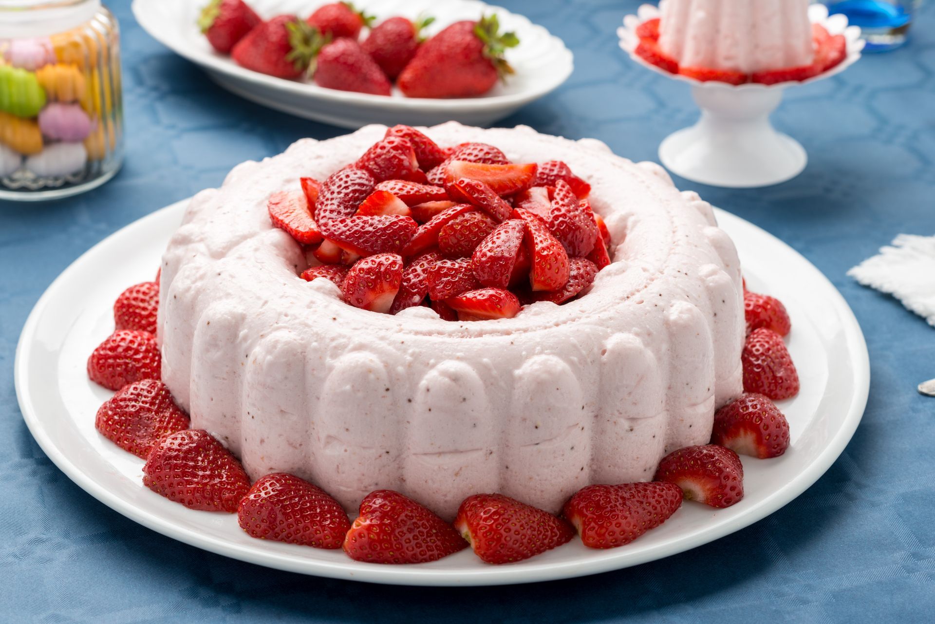 Gâteau mousse aux fraises garni et entouré de fraises fraîches, présenté sur une assiette blanche.