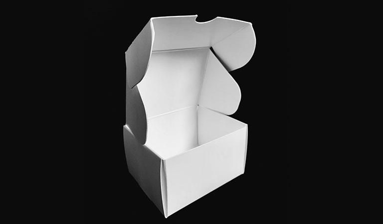 Eine weiße Schachtel mit geöffnetem Deckel auf schwarzem Hintergrund