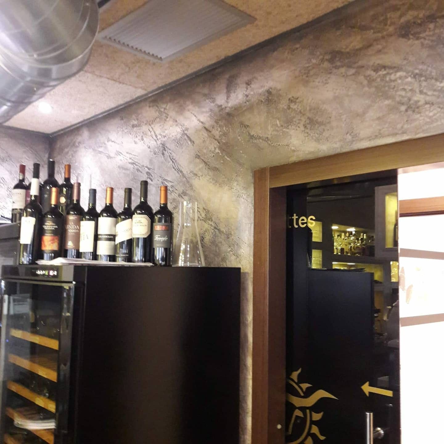 Botellas de vino expuestas sobre un aparador oscuro en el interior de un restaurante o bar con poca luz