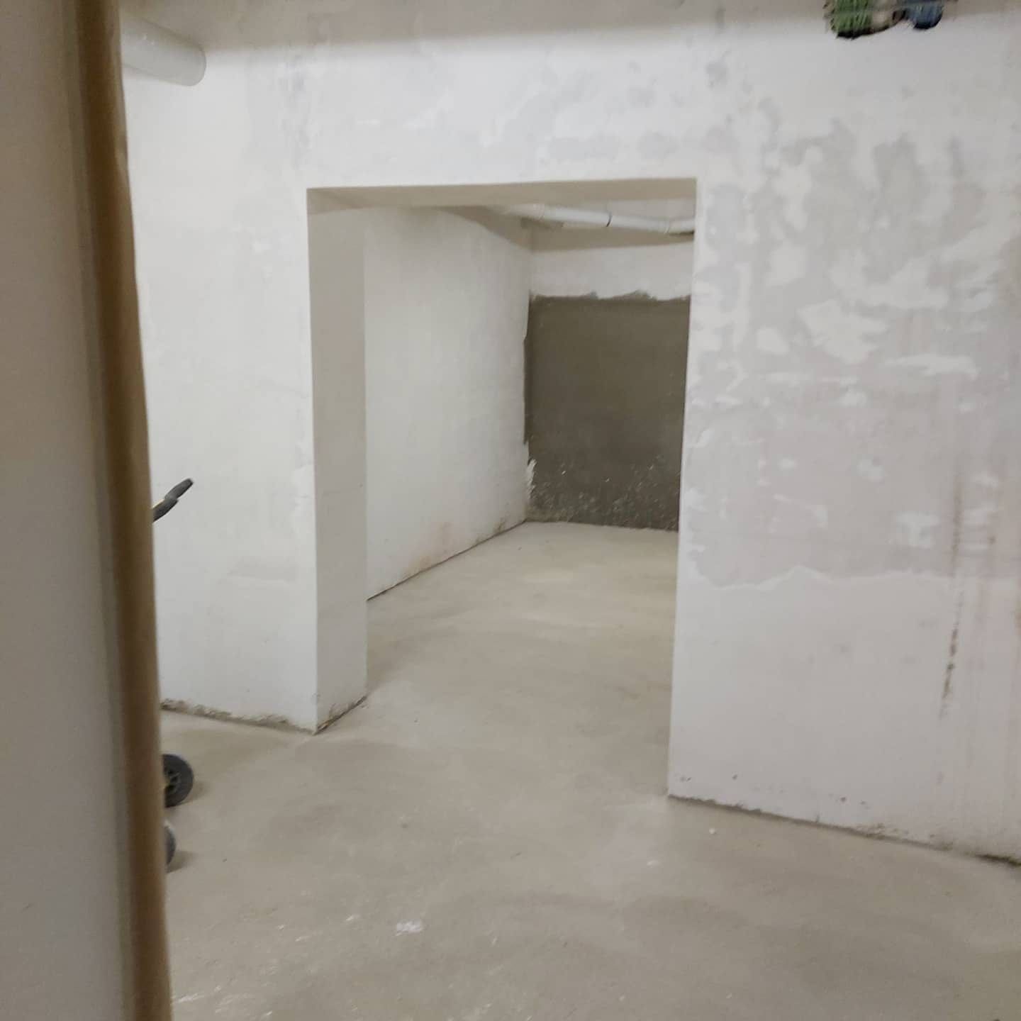 Habitación interior vacía y blanca, con paredes sin terminar y suelo de hormigón