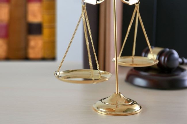 Una balanza de la justicia está sobre una mesa al lado del mazo de un juez.
