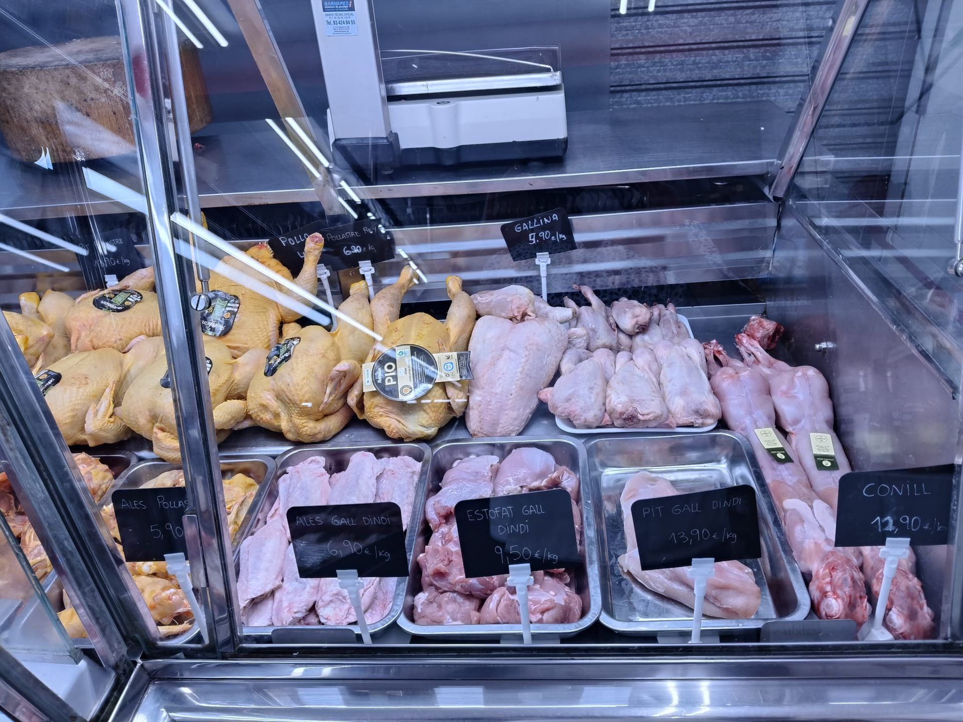 Una vitrina llena de carne de pollo y conejo en una carnicería.