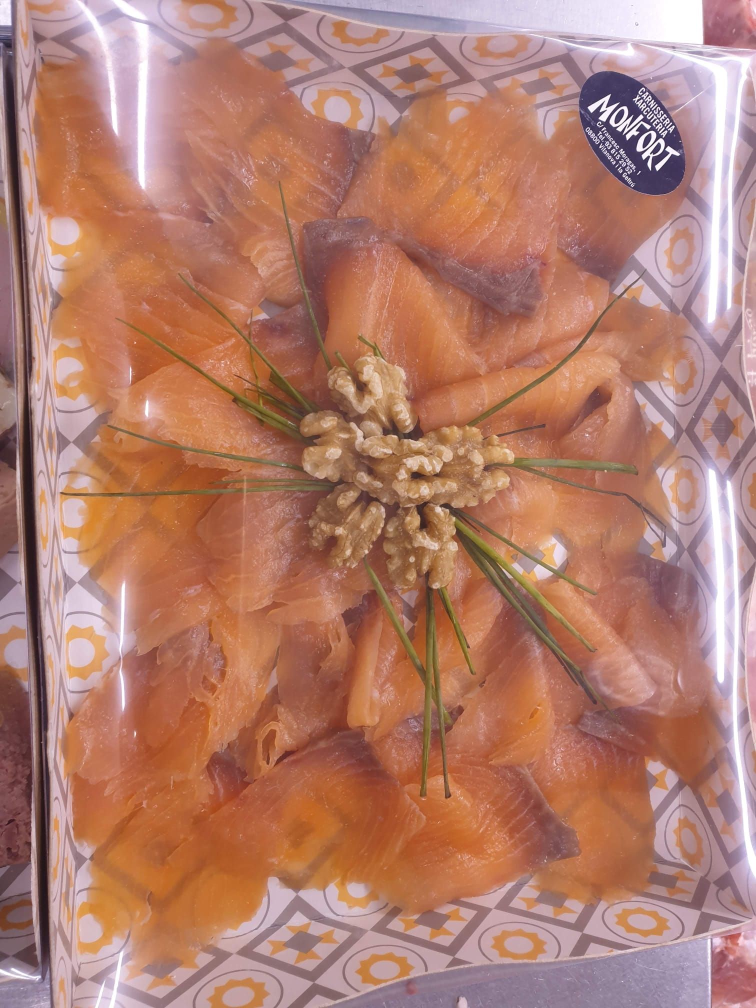 Una caja de salmón ahumado con nueces y cebollino encima.