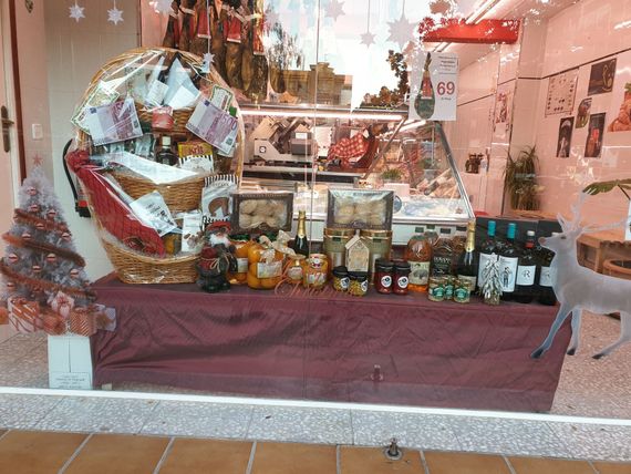 Una exhibición de comida en el escaparate de una tienda con un árbol de Navidad al fondo.