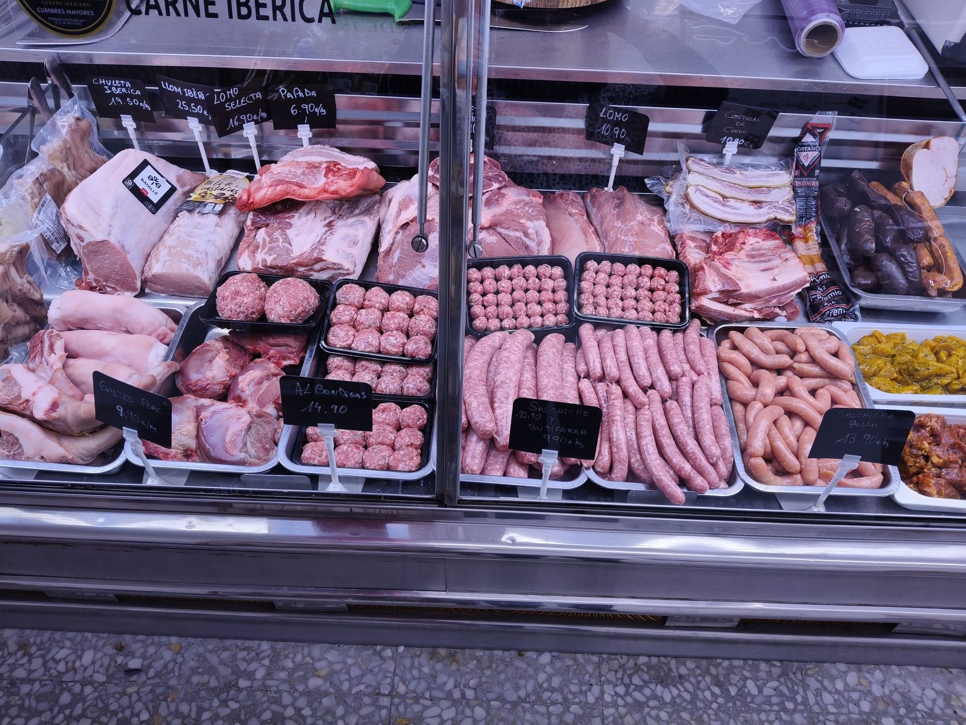 Una vitrina de carnicería llena de carne y embutidos.