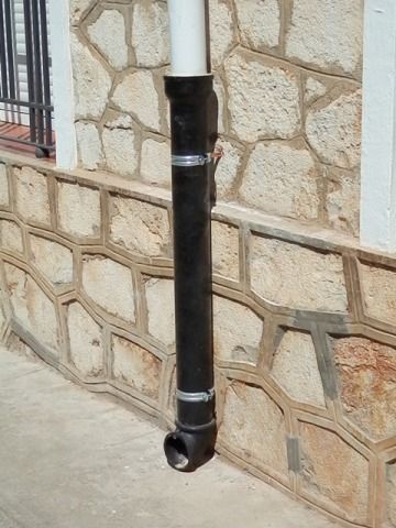 Un tubo negro está unido al costado de una pared de piedra.