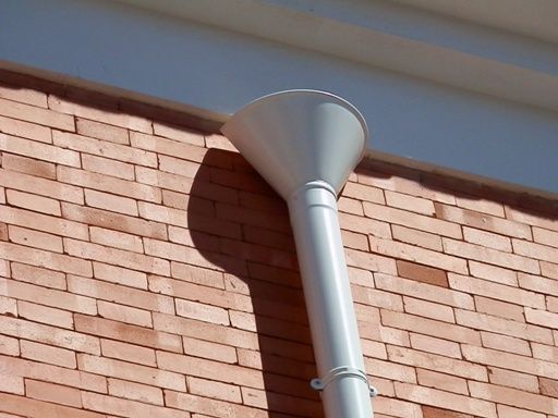 Un tubo blanco está unido a una pared de ladrillos.