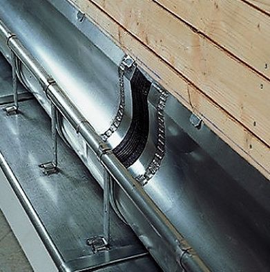 Una canaleta de metal está fijada a una pared de madera.