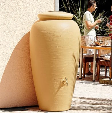 Un gran jarrón amarillo se encuentra en un patio junto a una mesa y sillas.