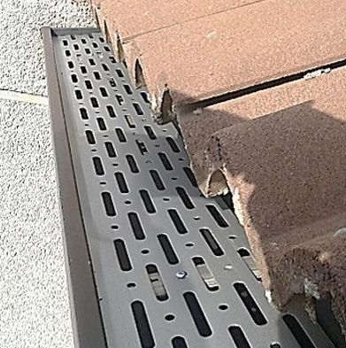 Un primer plano de un desagüe de metal en una pared de ladrillos.