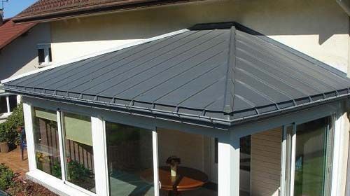 Una casa con techo gris y una mesa en el porche