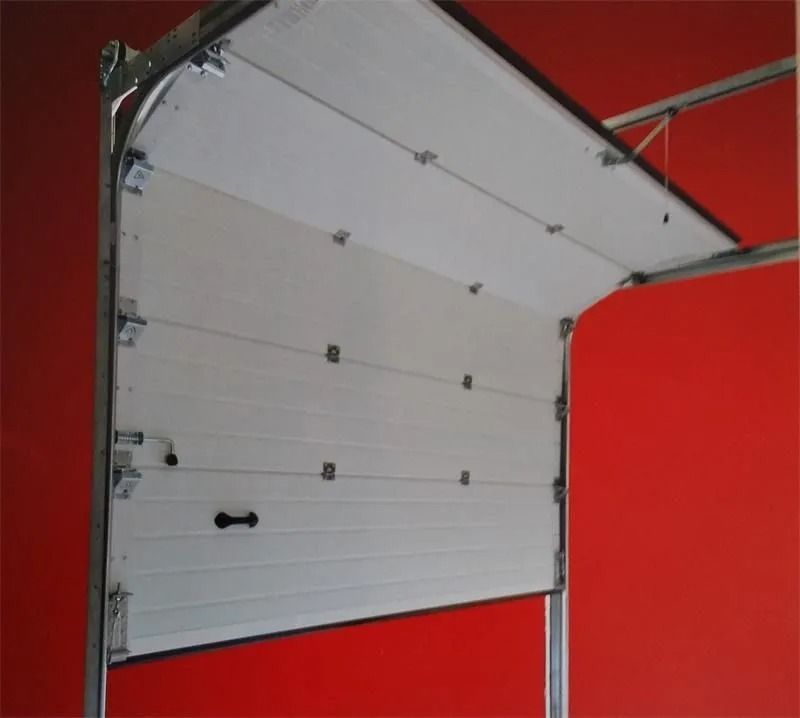 Una puerta de garaje blanca está abierta contra una pared roja.