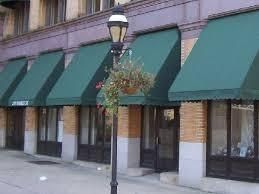 Toldos verdes sobre las fachadas de las tiendas en un edificio de ladrillo con una farola delante.