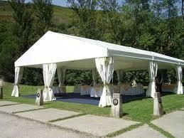 Carpa blanca con laterales drapeados, instalada sobre el césped, con mesas en el interior.