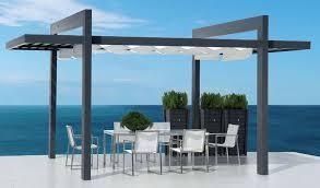 Pérgola con mesa y sillas de comedor en un patio con vista al mar.