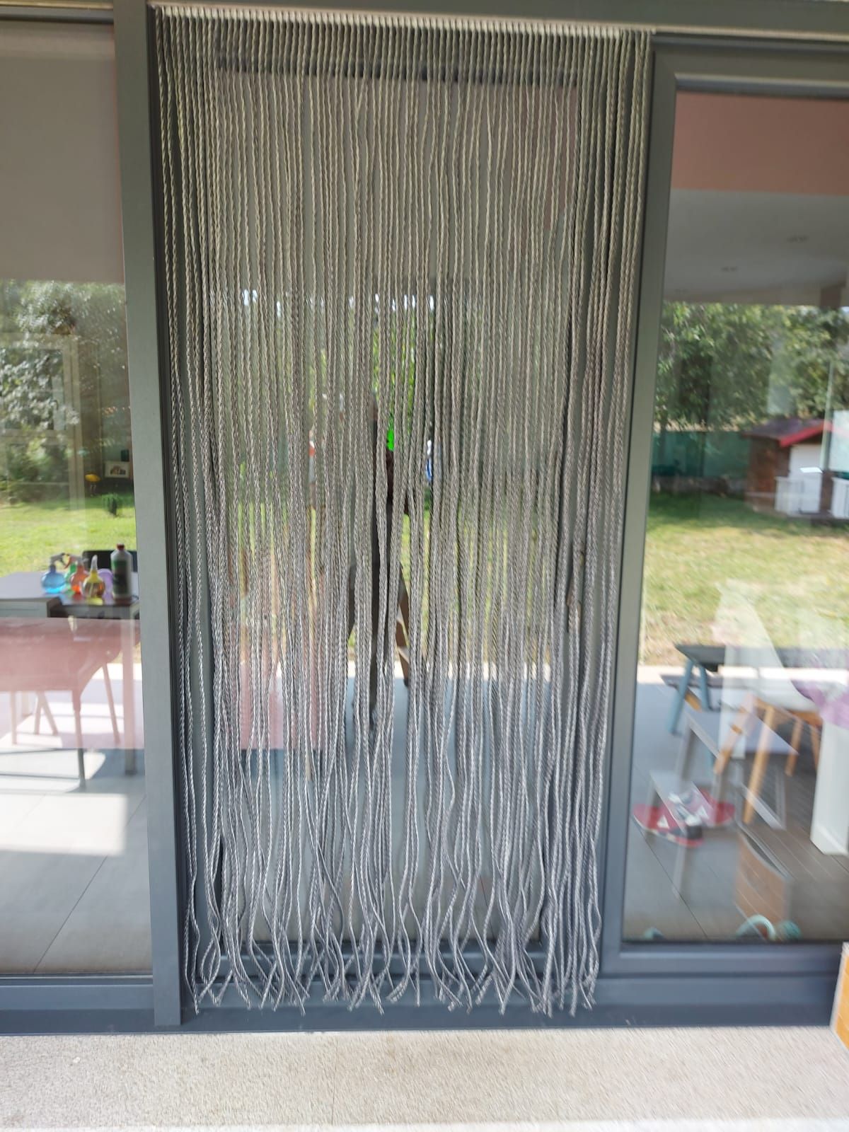 Una cortina de plata cuelga de una puerta corrediza de vidrio.