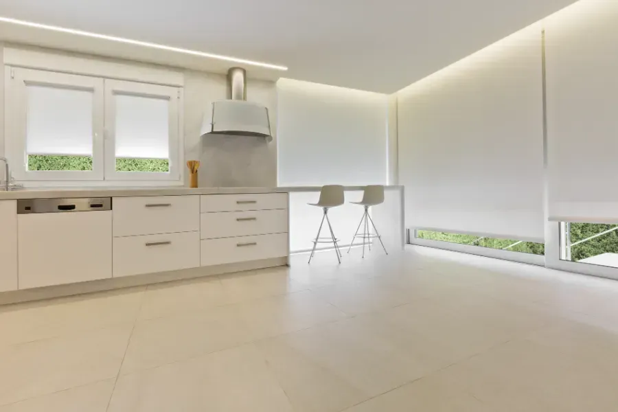 Una cocina vacía con gabinetes blancos, taburetes y una estufa.