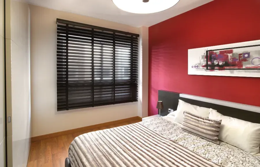 Un dormitorio con una cama y una pared roja.