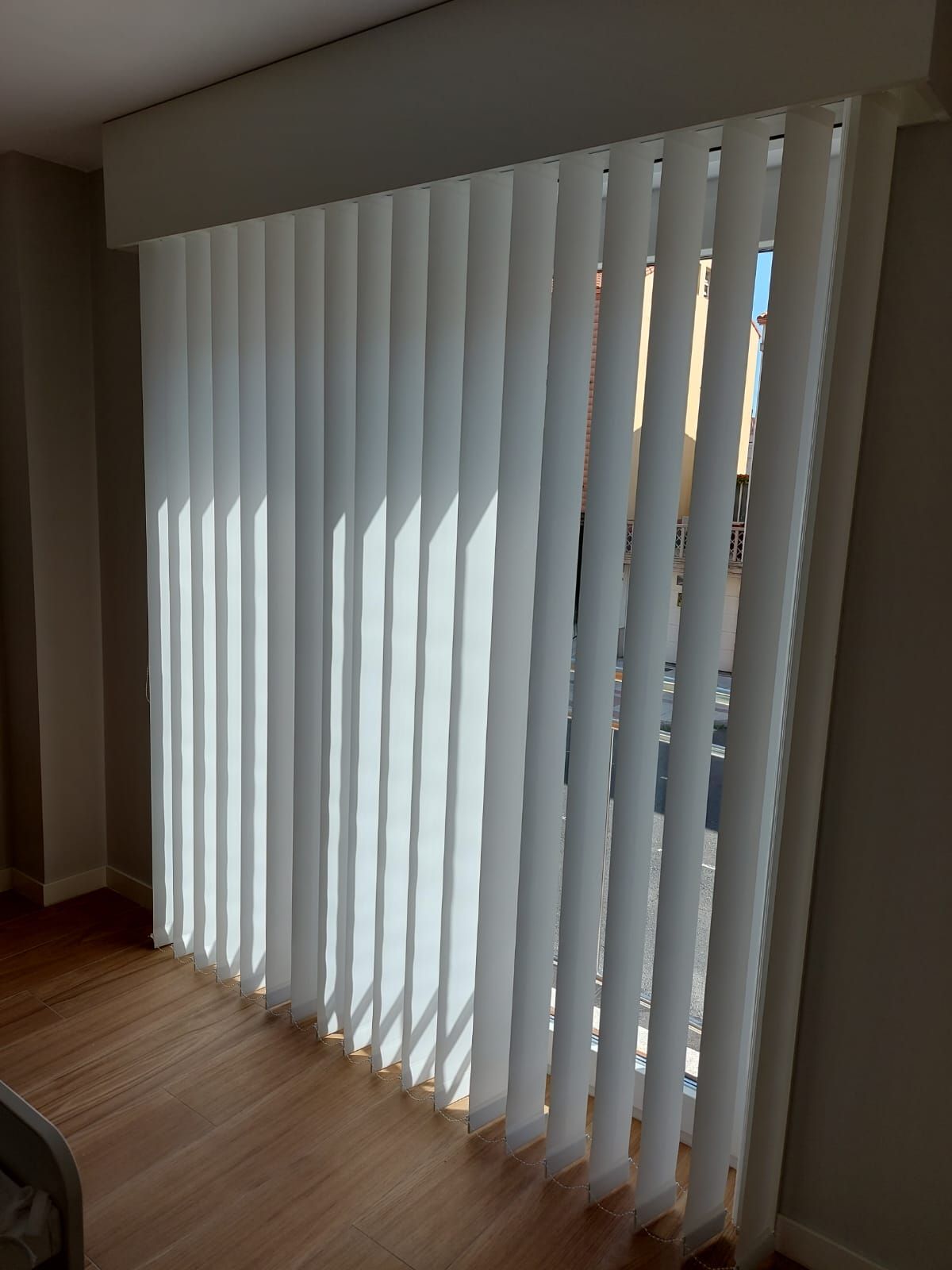 Una sala de estar con persianas verticales blancas sobre una puerta corrediza de vidrio.