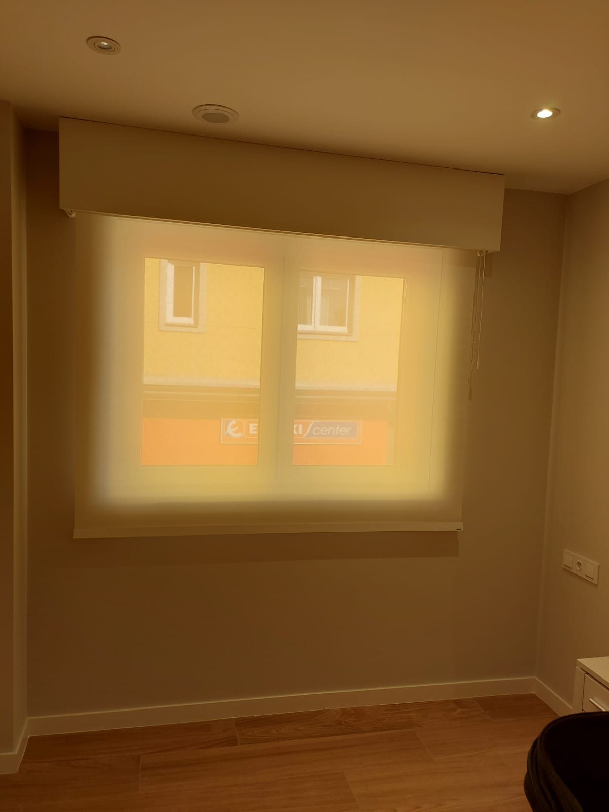 Una habitación con dos ventanas y una persiana blanca en la ventana.