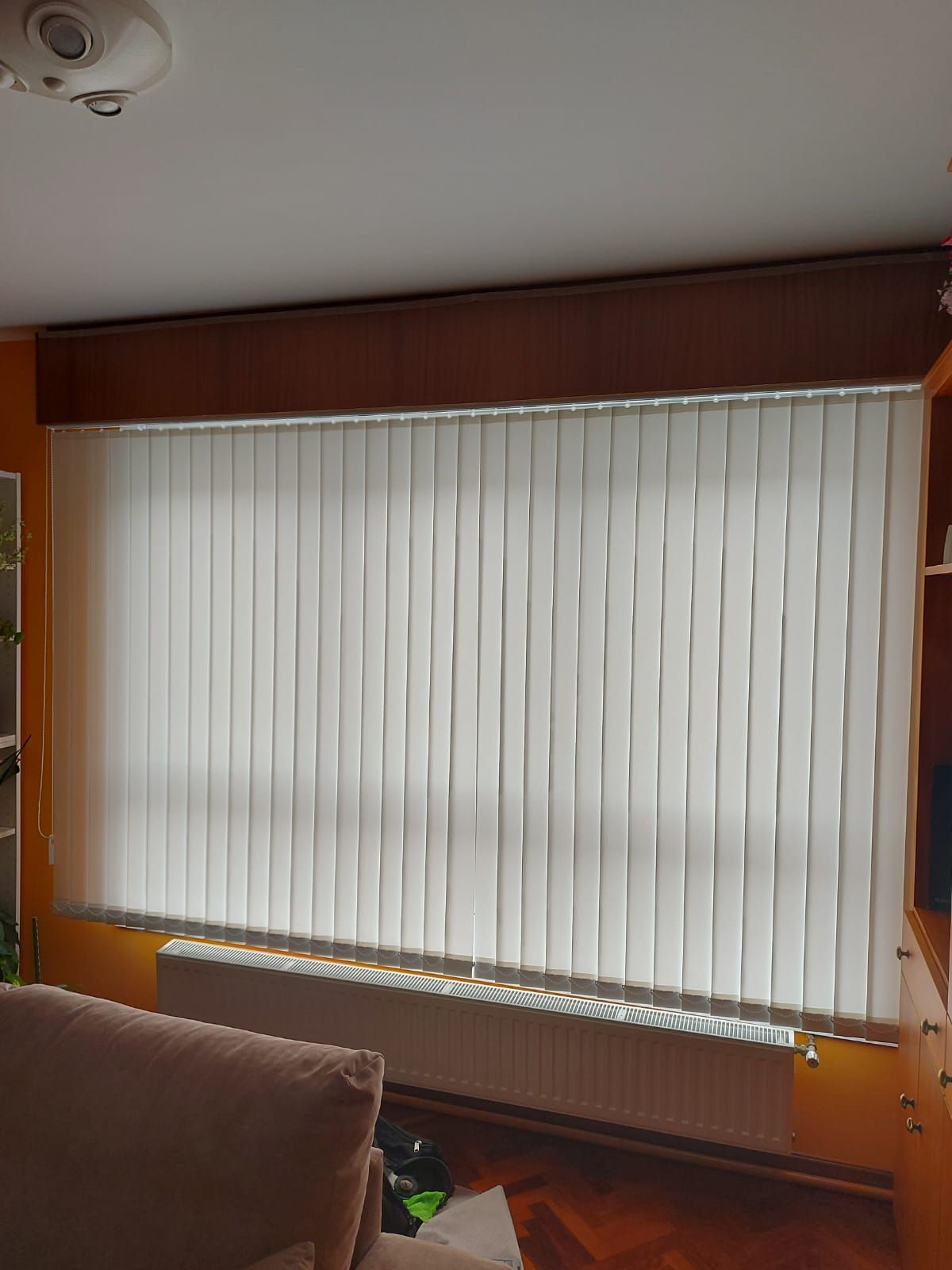 Una sala de estar con un sofá y una ventana con persianas verticales.