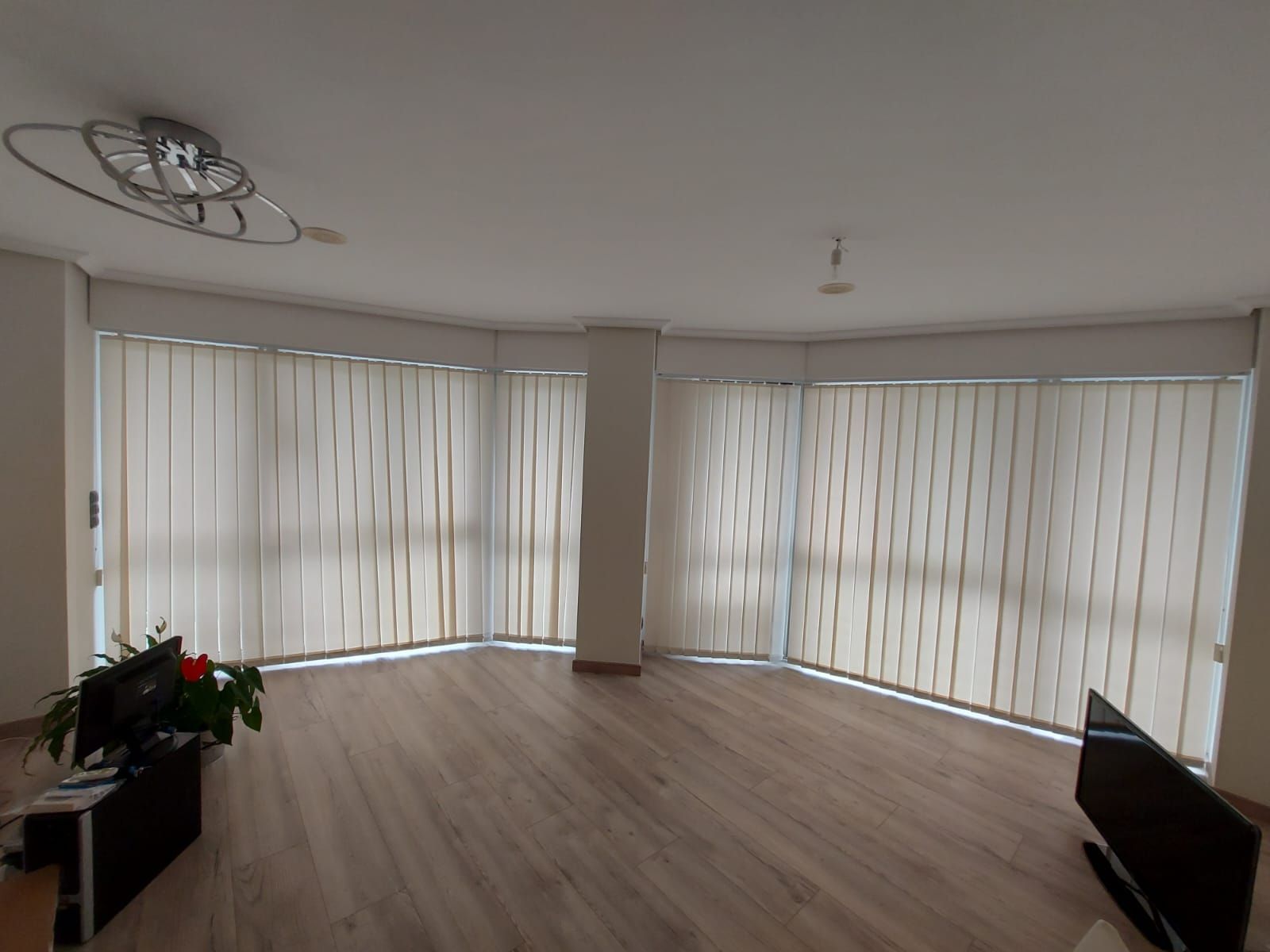Una sala de estar con muchas ventanas y persianas verticales.