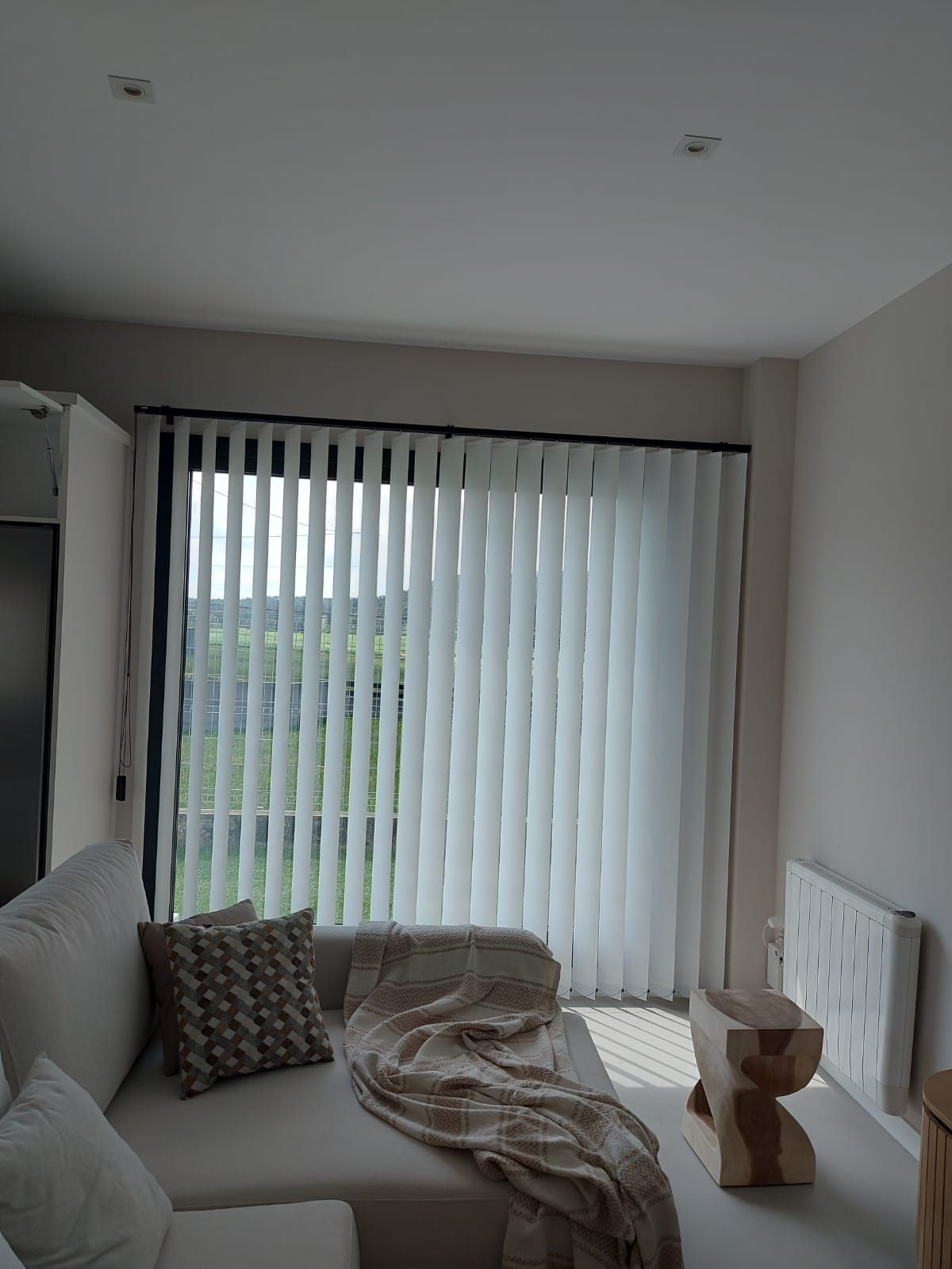 Una sala de estar con un sofá y una ventana con persianas verticales.