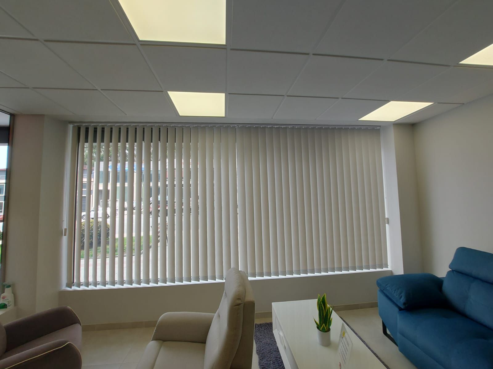 Una sala de estar con un sofá azul y persianas blancas.