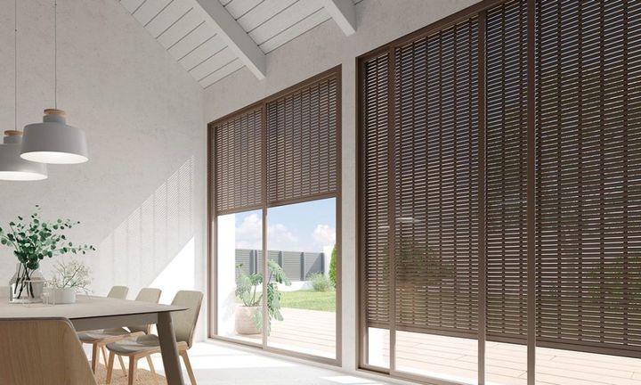 Un comedor con mesa y sillas y puertas corredizas de vidrio con persianas de madera.