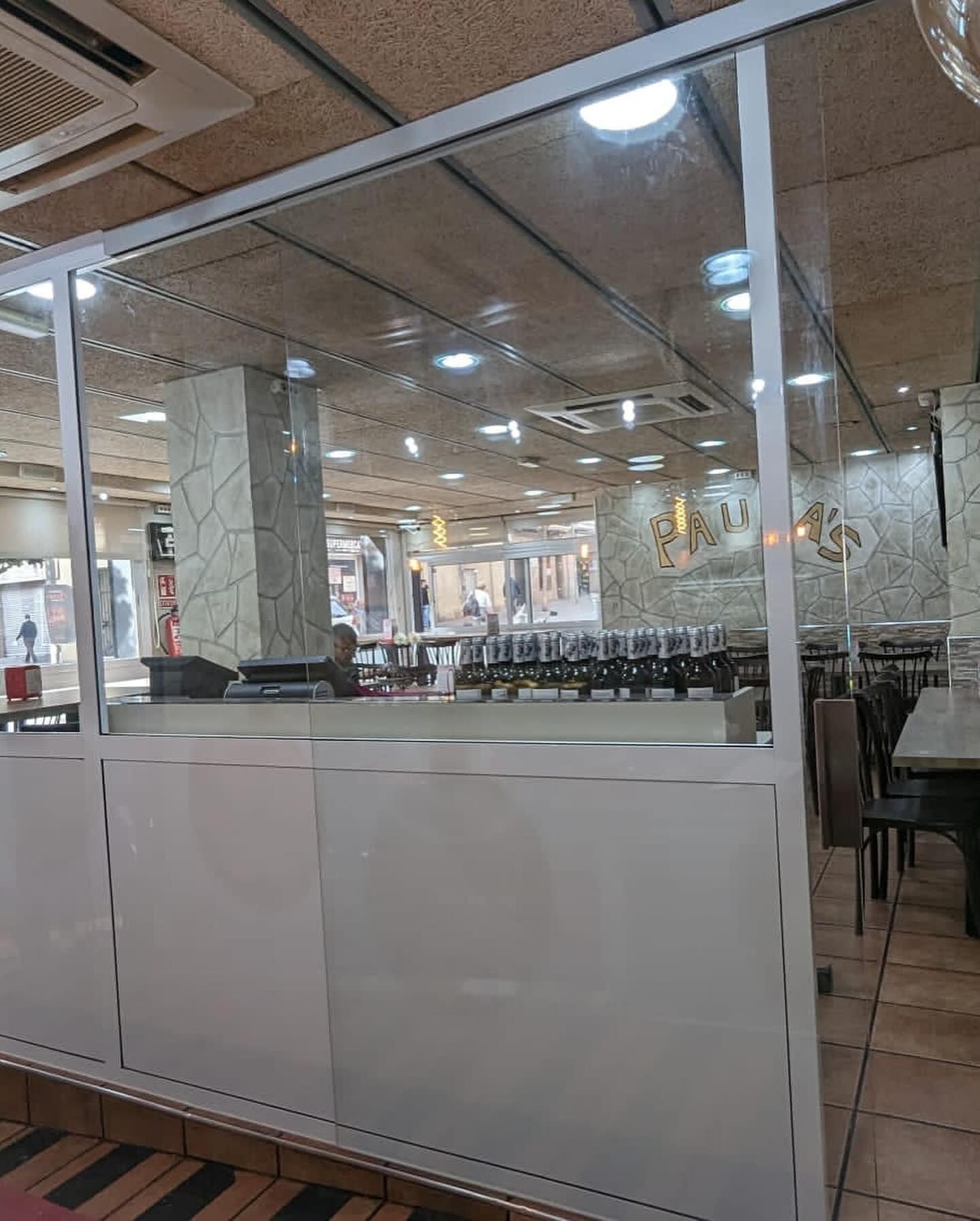 Un restaurante con mesas y sillas detrás de una pared de cristal.